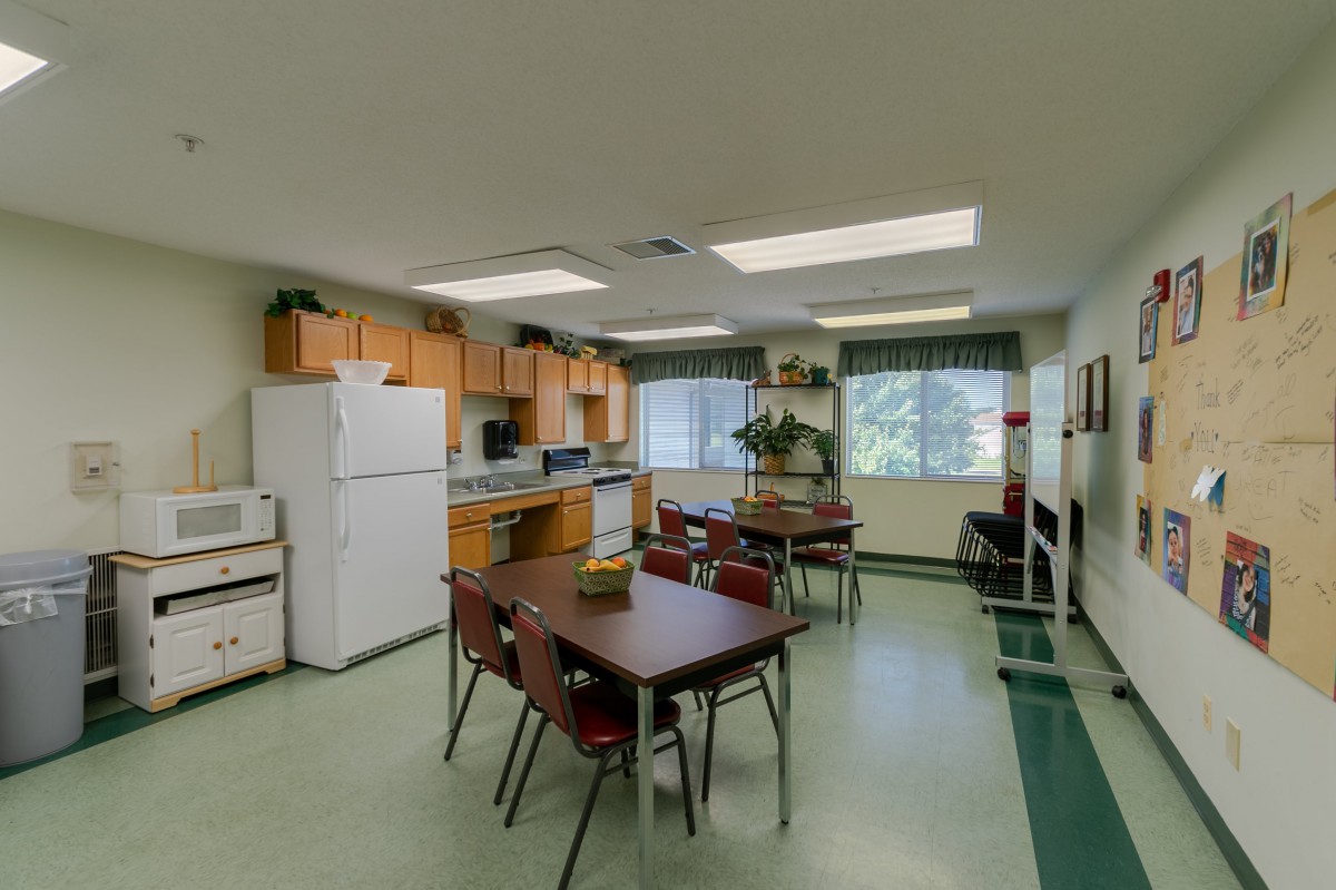 A communal kitchen and dining area with tables, chairs, and appliances.