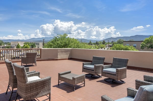 Outdoor patio with wicker furniture and a scenic mountain view under a clear blue sky.