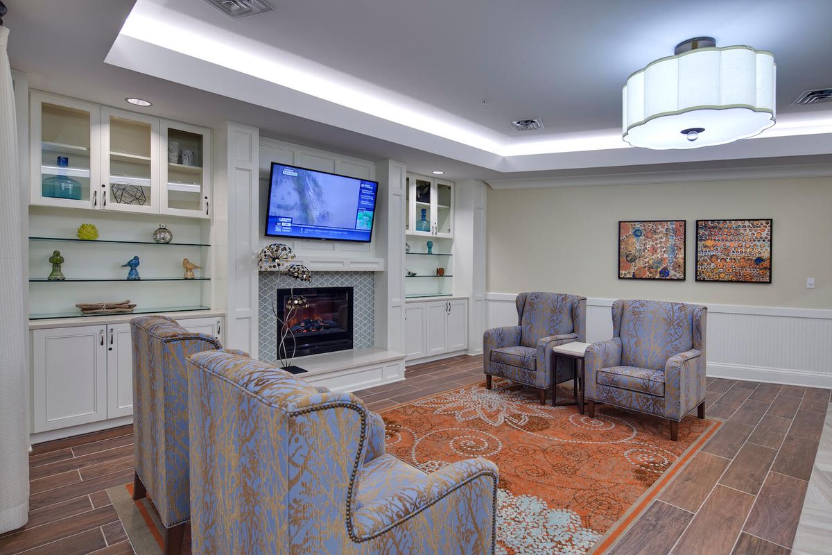 A cozy living room with armchairs, a fireplace, and a mounted television.