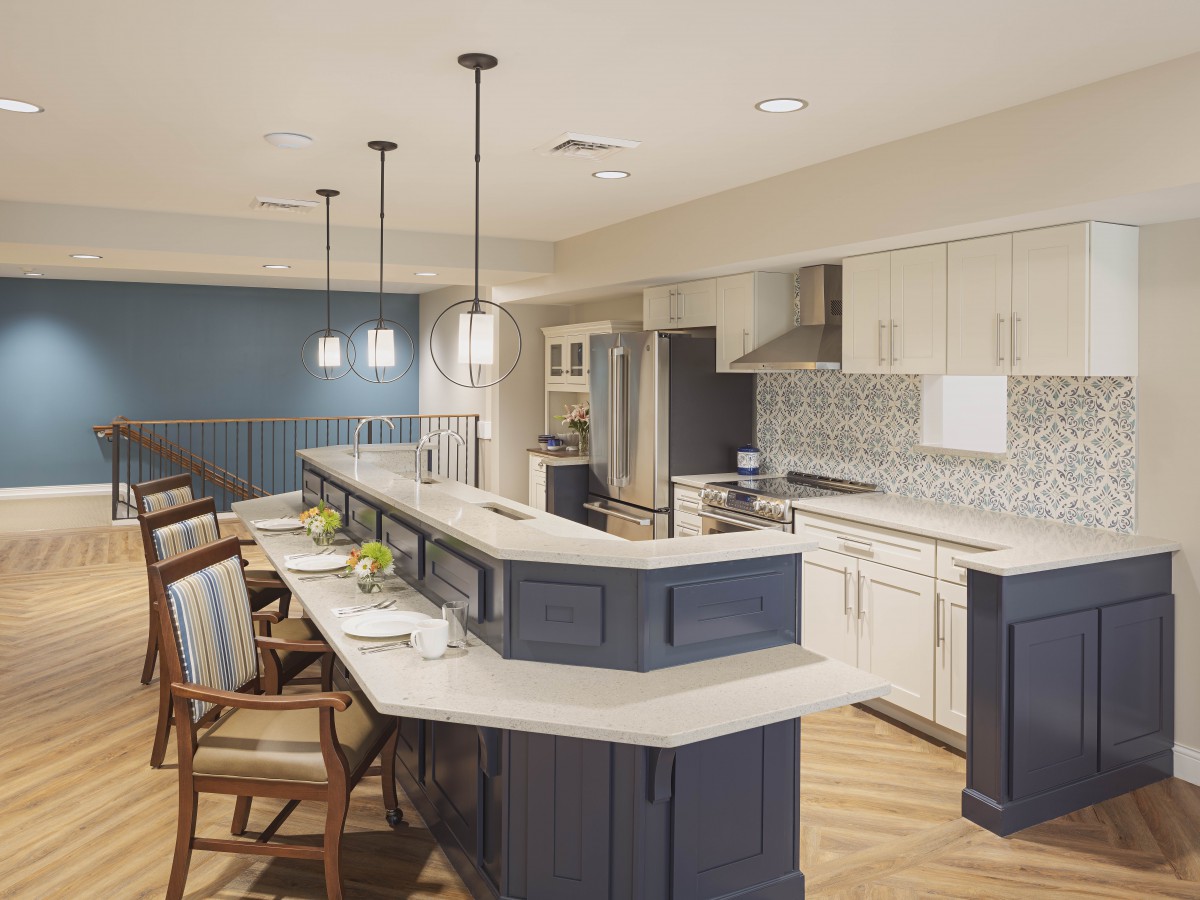 A modern kitchen with white cabinets, a large countertop, and stylish pendant lights.