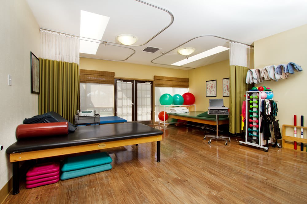 A well-equipped physical therapy room with exercise tables and equipment.