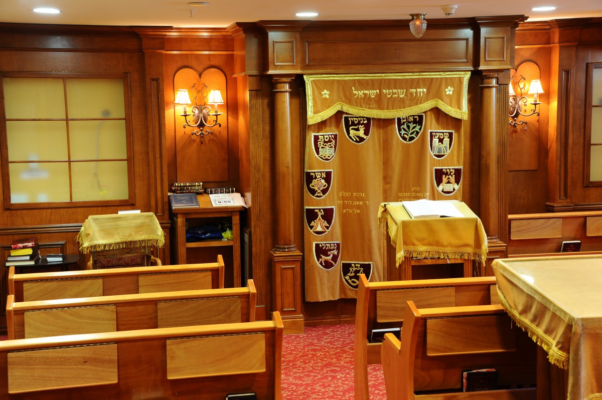 A small synagogue featuring wooden seating and a Torah ark, designed for intimate prayer gatherings.