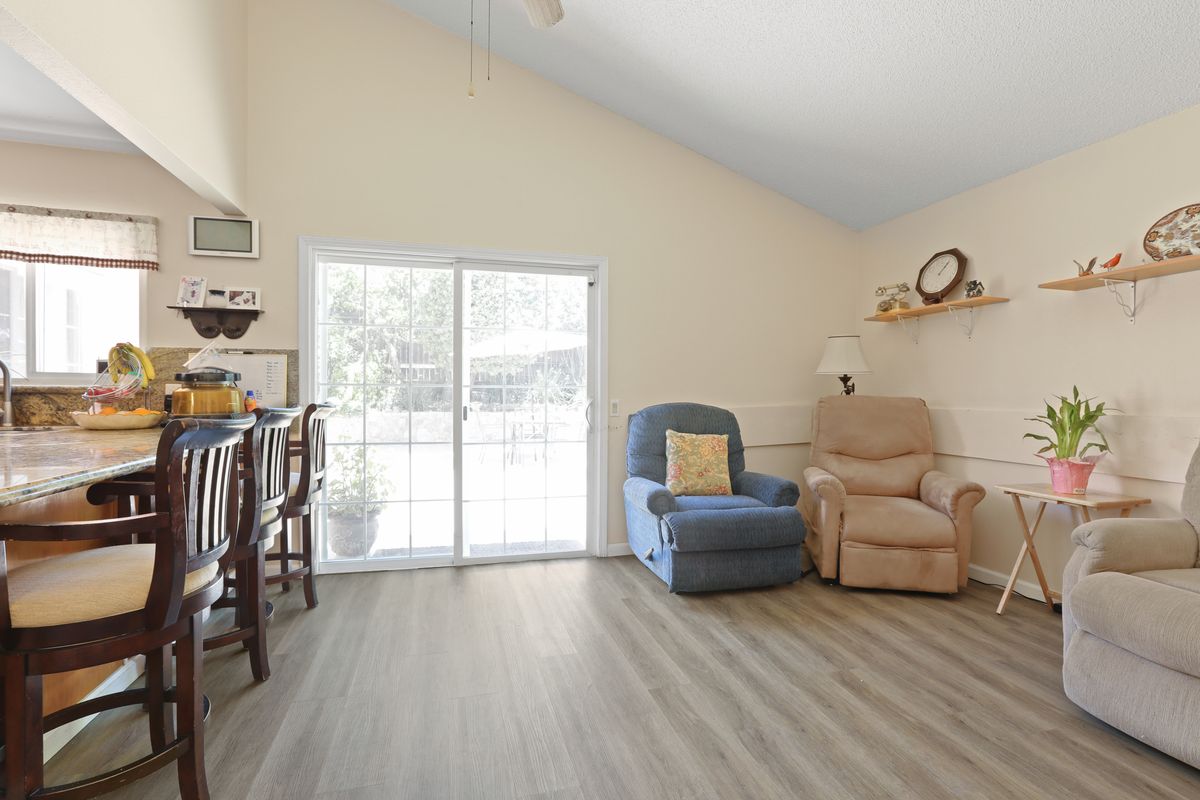 A cozy living room with two armchairs, wood flooring, and a sliding glass door letting in natural light.