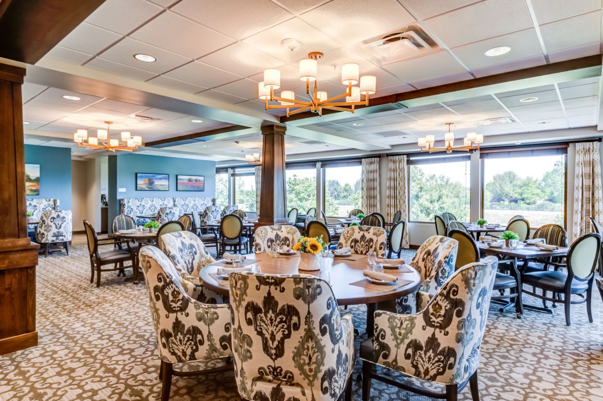 A beautifully decorated dining room featuring elegant chairs, chandeliers, and large windows with scenic views.