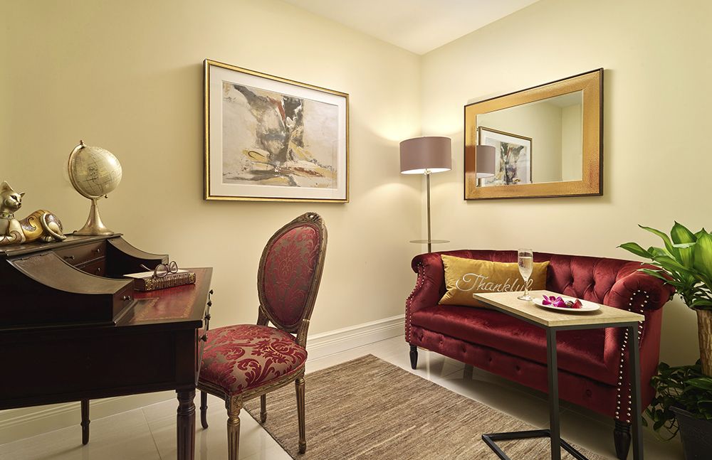 A cozy living room with elegant furniture, including a red sofa and an ornate chair.