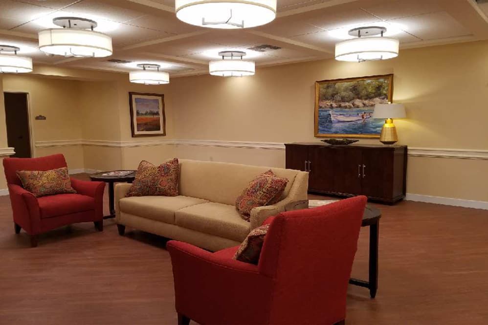 A cozy living room with a comfortable sofa, red chairs, and stylish lighting.