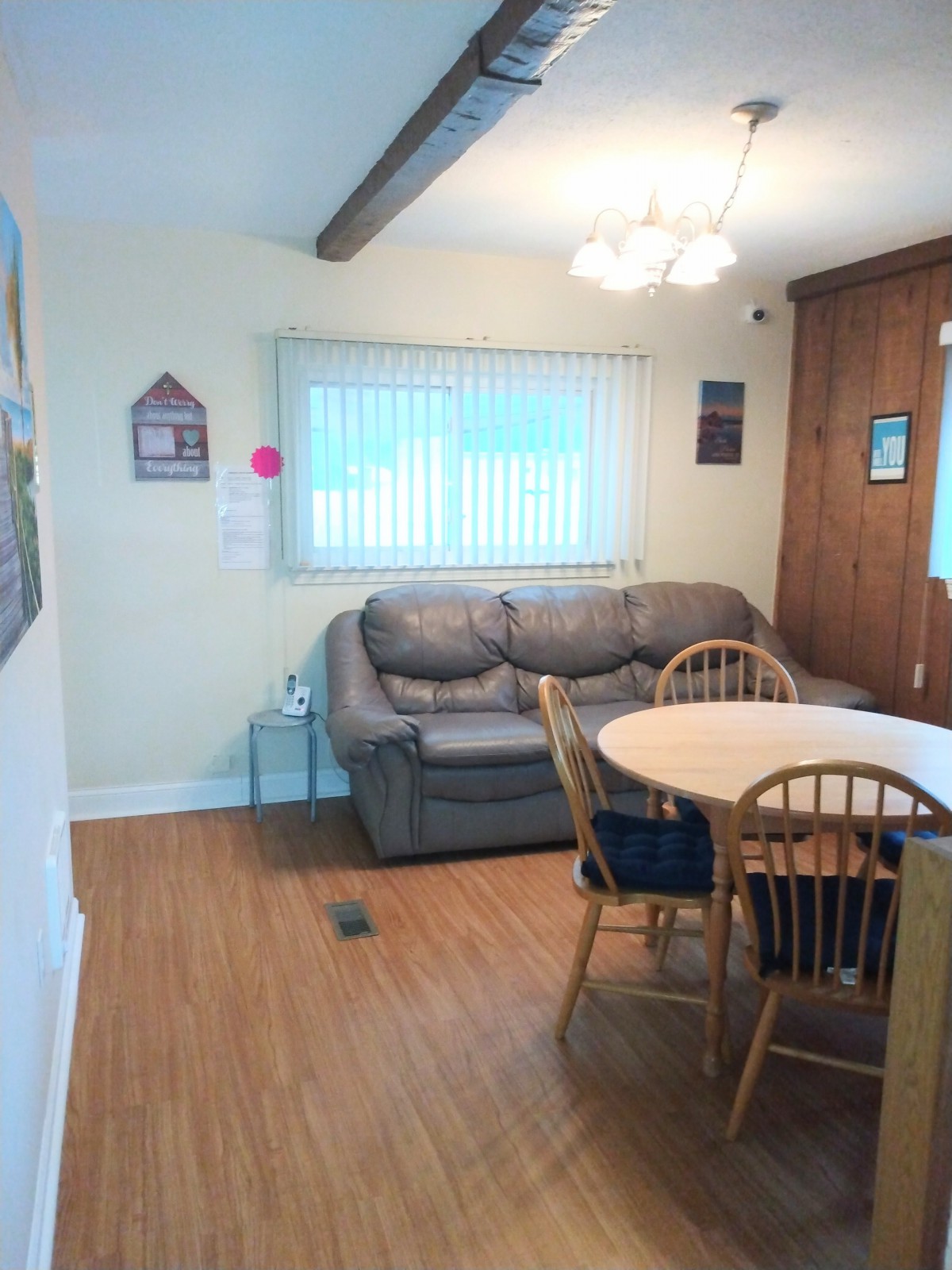A cozy living and dining space featuring a sofa, round dining table with chairs, and window blinds.