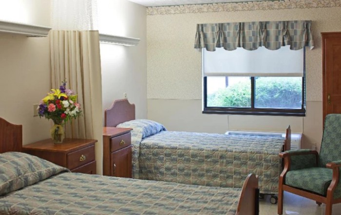 A hospital room with two beds and a window.
