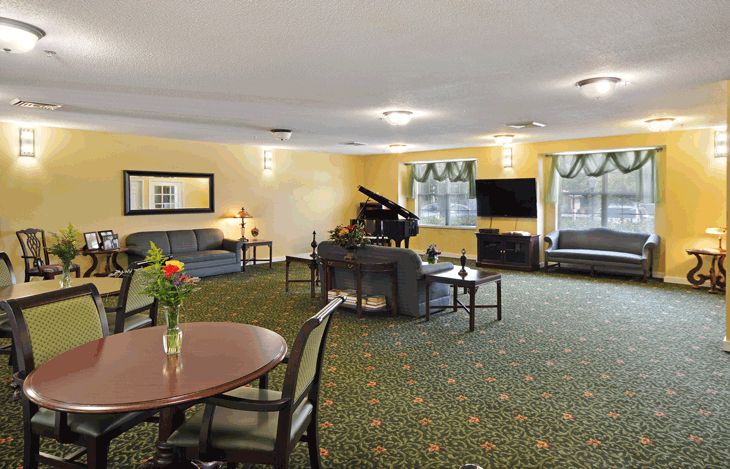 A spacious living room featuring a grand piano, ample seating, and a television.