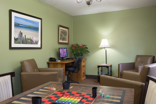 A cozy lounge area featuring comfortable seating, a computer workstation, and a board game ready for play.