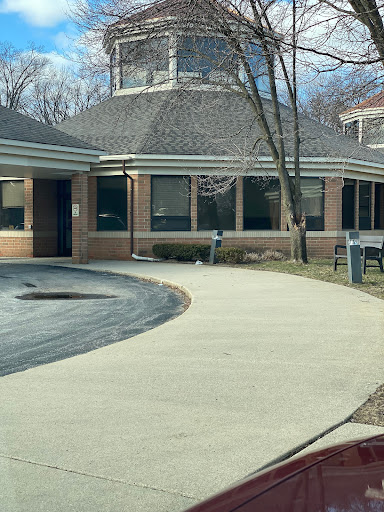 A view of a building with a curved sidewalk and trees in the surroundings.