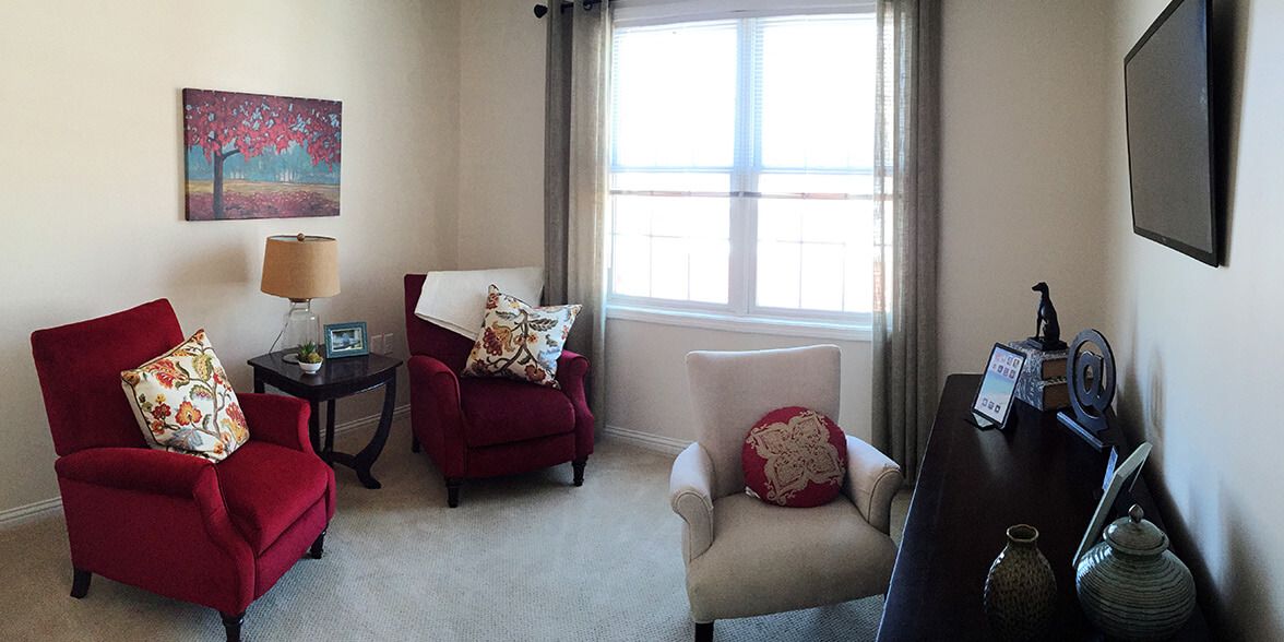 A cozy living room corner with armchairs and a large window letting in natural light.
