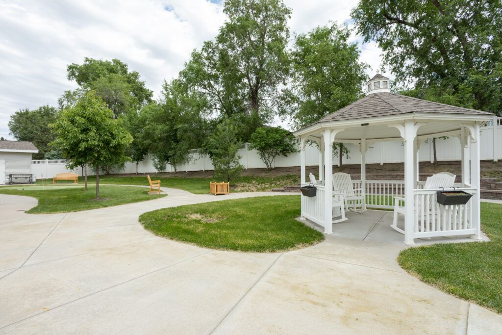 A serene outdoor setting featuring a white gazebo along a winding pathway surrounded by lush greenery.
