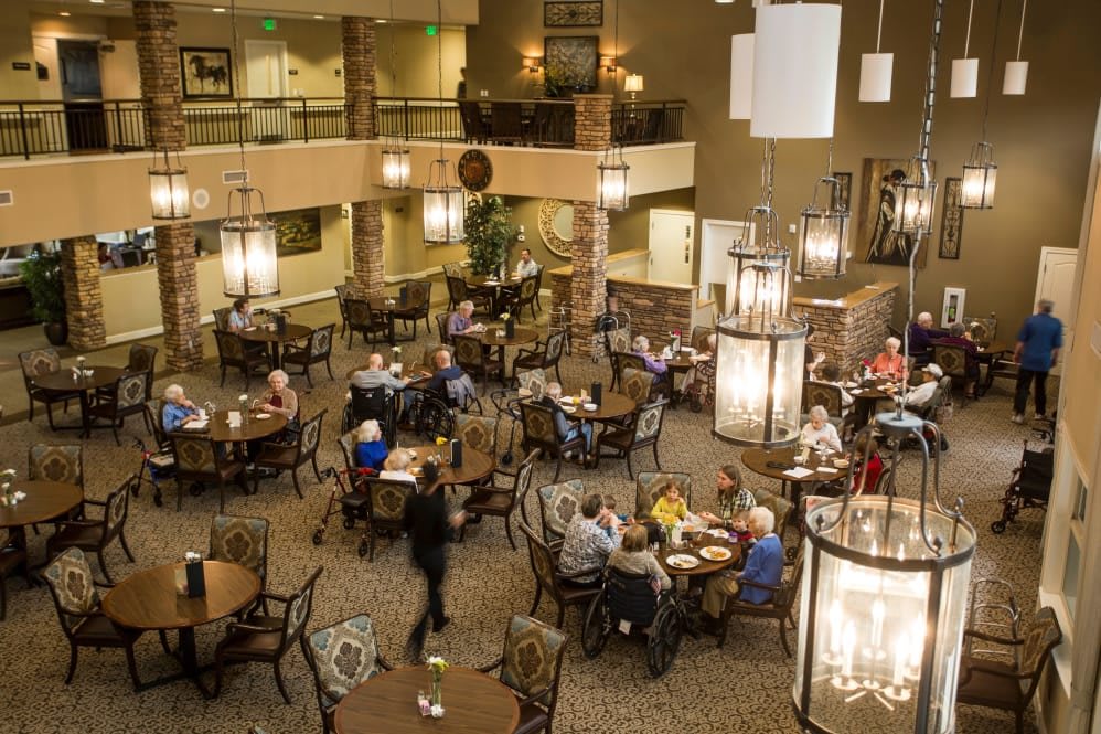 A lively dining area with people gathered at tables, enjoying a meal in a warmly lit setting.