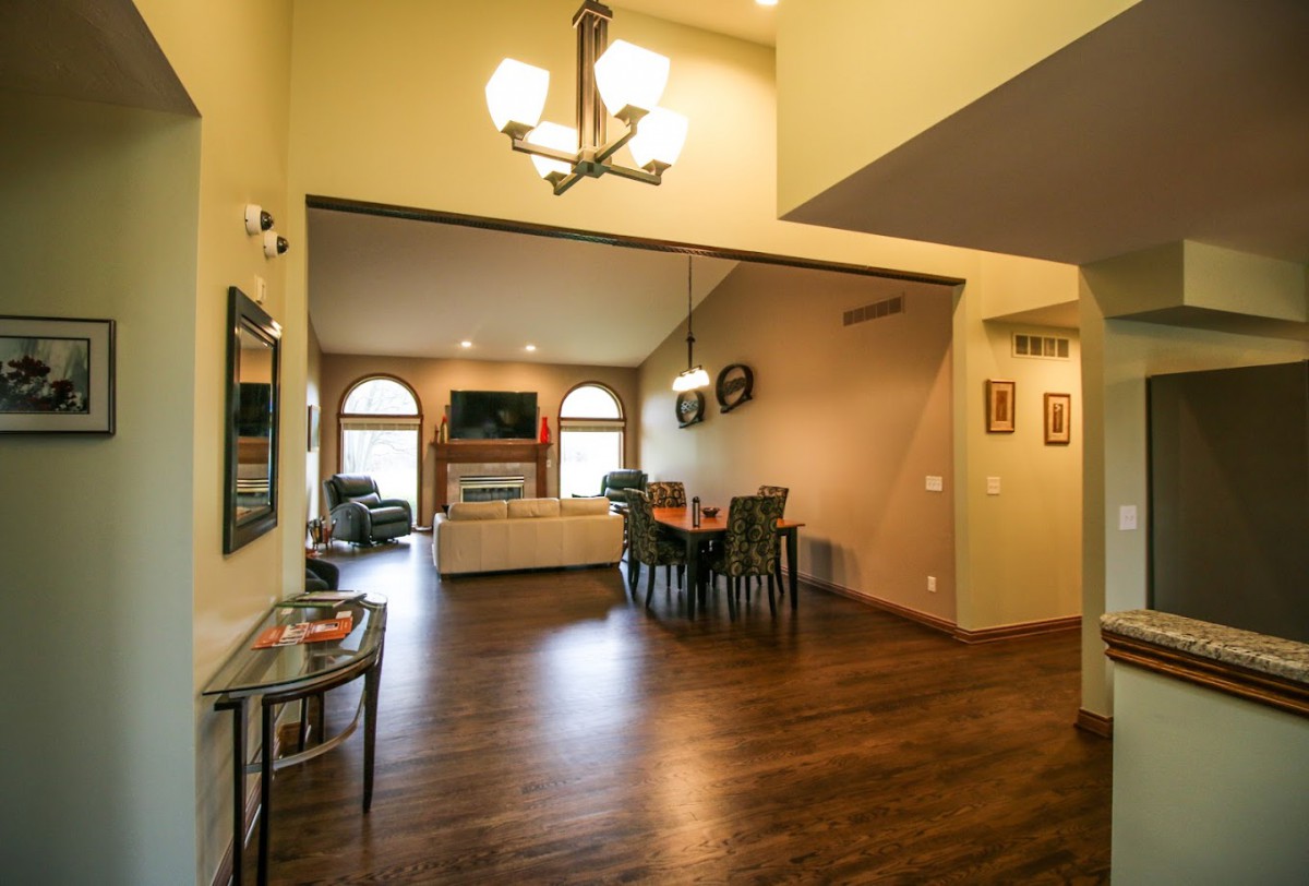 Spacious living and dining area with vaulted ceilings, elegant chandelier, and wood flooring.