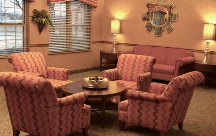 A cozy living room with pink patterned furniture and warm lighting.