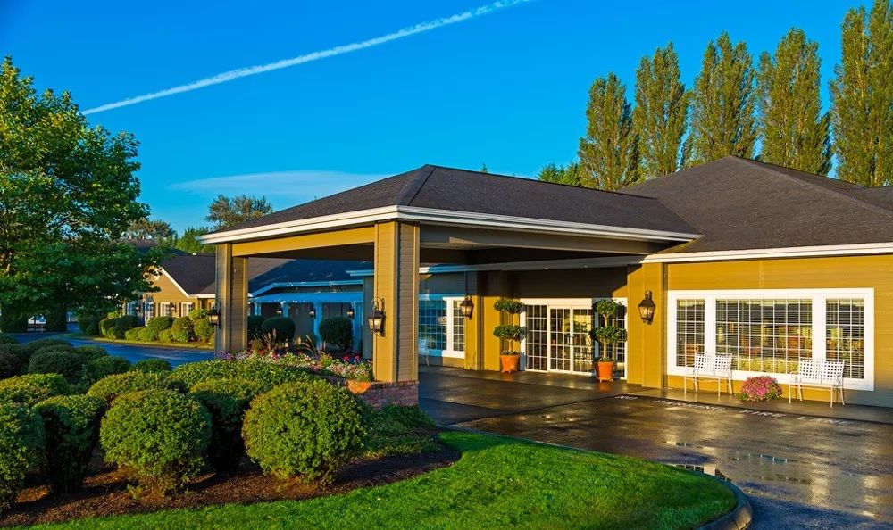 A beautifully lit building entrance surrounded by lush greenery under a clear blue sky.