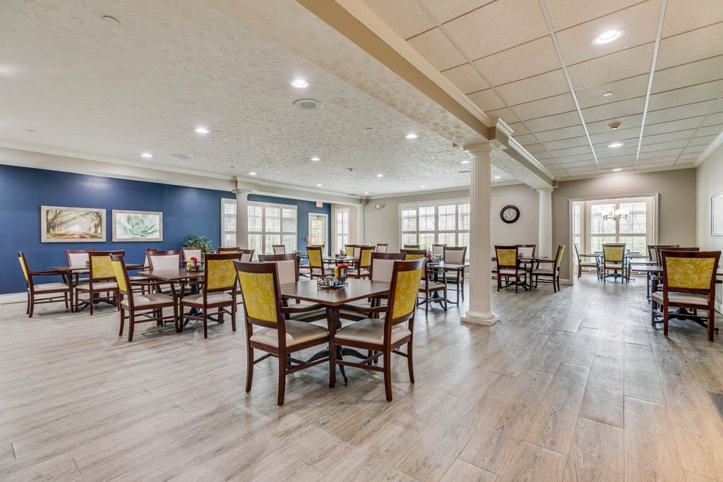 A spacious, elegantly designed dining area with neatly arranged tables and chairs, featuring a modern interior with bright lighting.