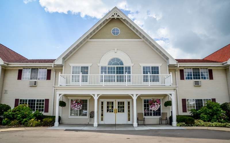 A symmetrical building with a prominent entrance and balcony, set against a cloudy sky.