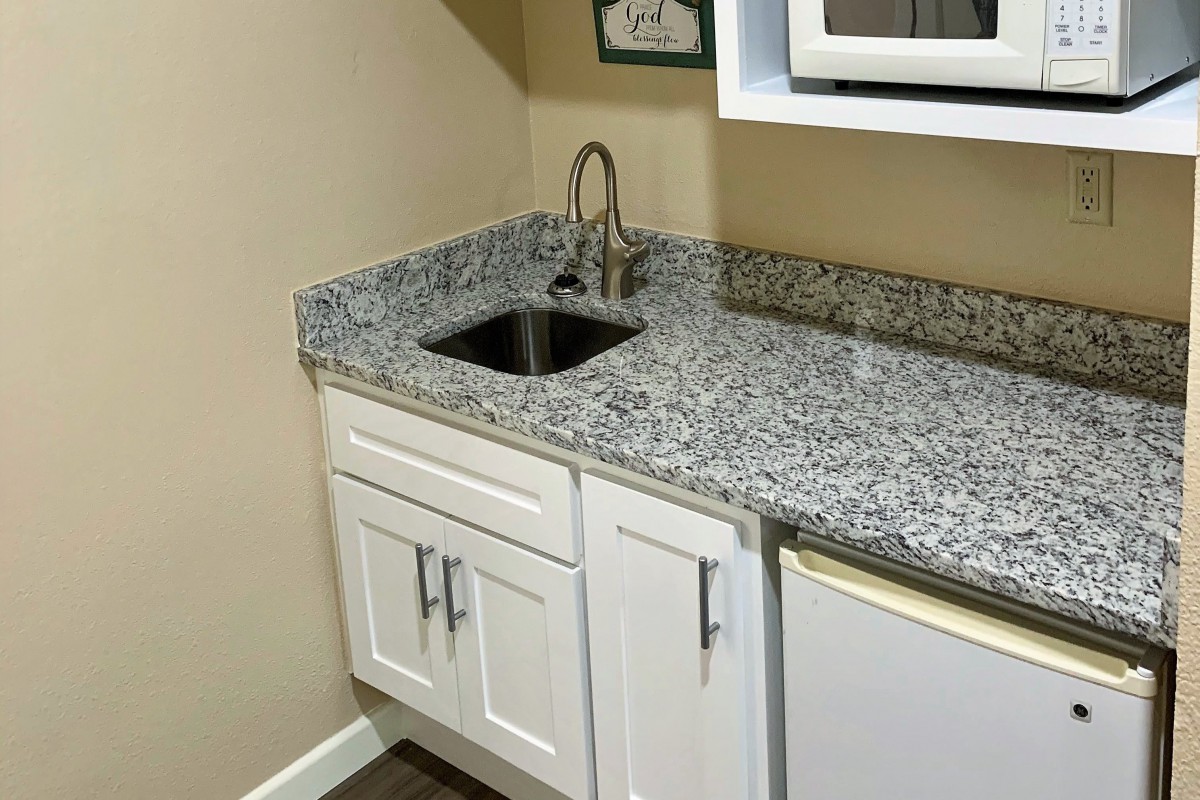 A small kitchen area with a granite countertop and a stainless steel sink.