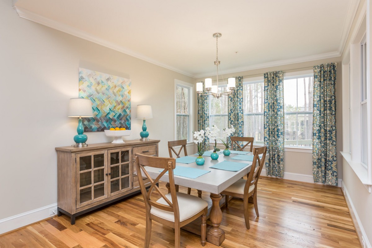 A bright and inviting dining room with a wooden table, elegant chairs, and tasteful decor.