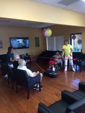 A group of people engaging in a game at a retirement home, with balloons decorating the room.
