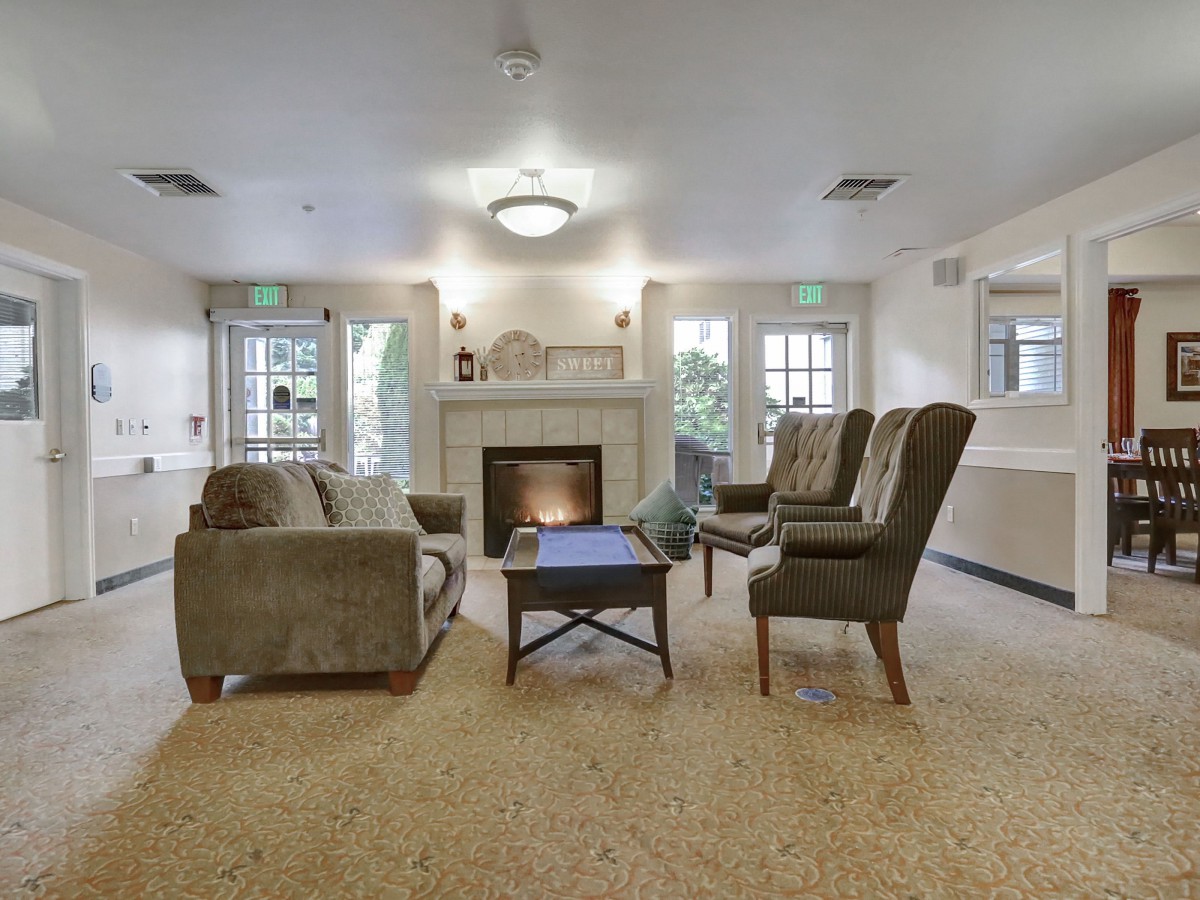 A cozy living room with a fireplace, sofa, armchairs, and a coffee table.