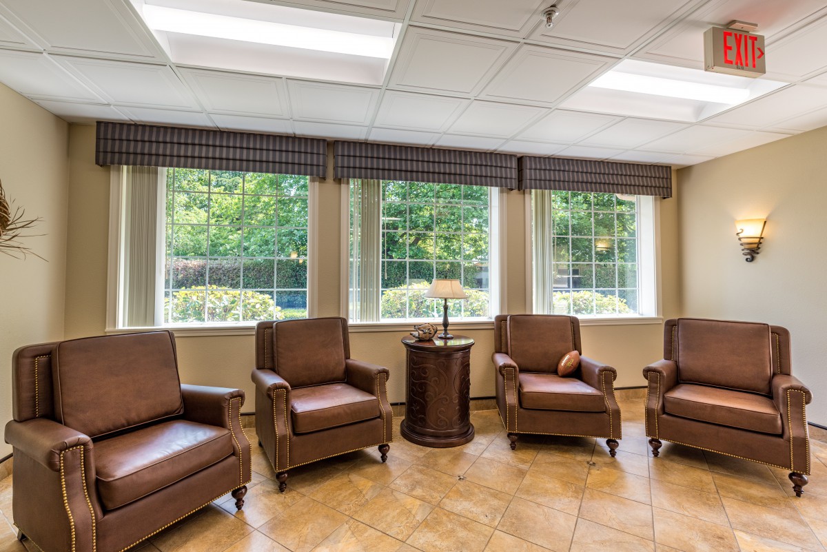 A cozy waiting room with four brown leather chairs and large windows providing natural light.