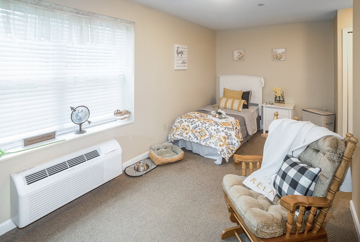 A cozy bedroom featuring a single bed, comfortable chair, and decorative items.