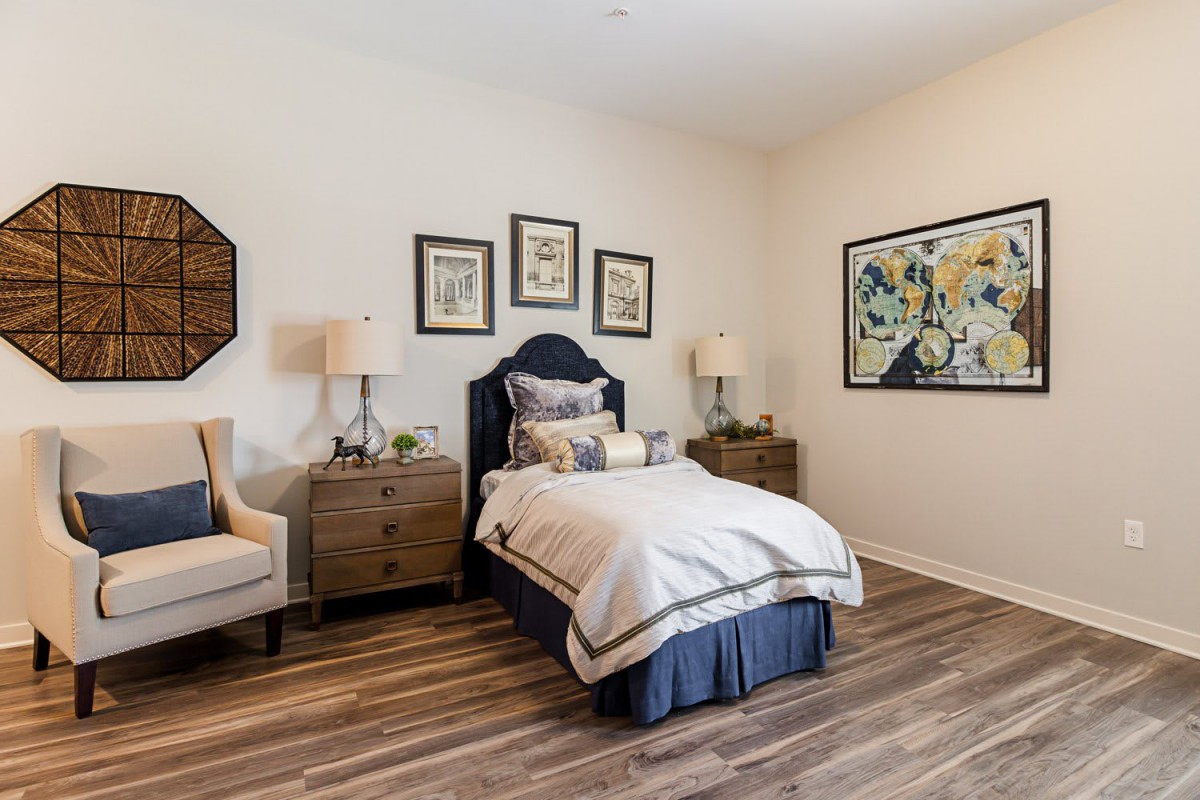 A cozy bedroom with a single bed, wooden floors, and decorative artwork on the walls.
