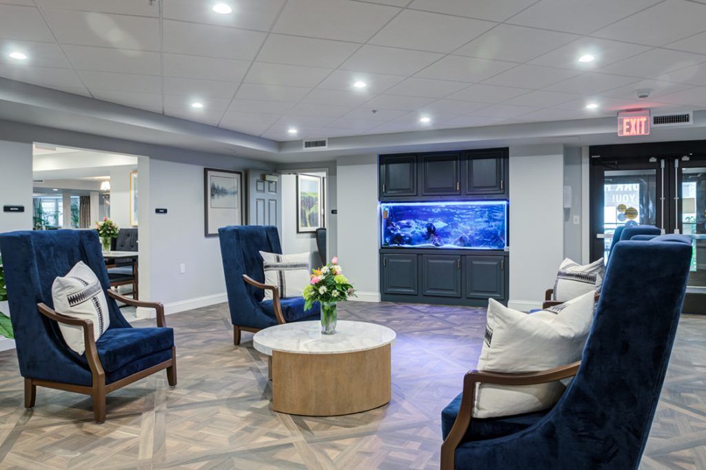 A modern living room with elegant seating, featuring a large aquarium and stylish decor.