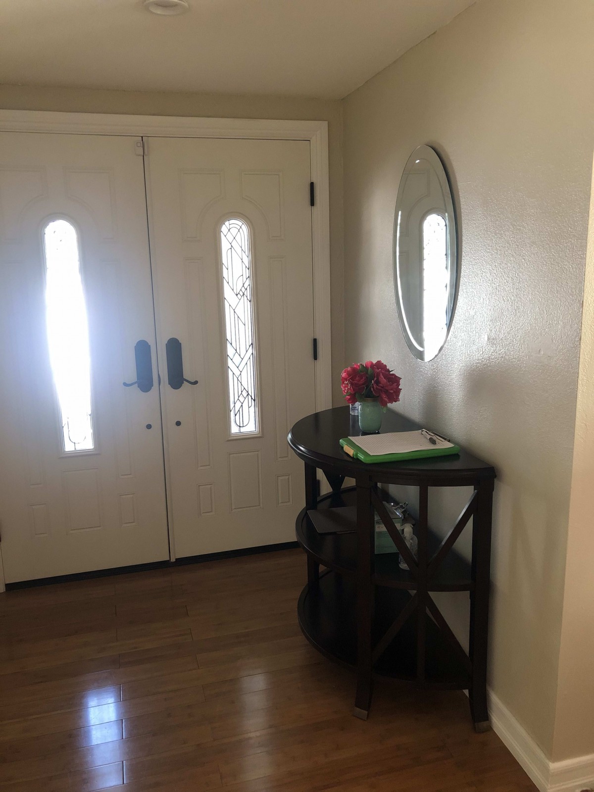 A home entryway featuring double doors, a console table with flowers and a mirror on the wall.