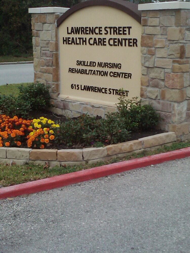 Sign for Lawrence Street Health Care Center with surrounding flowers and landscaping.