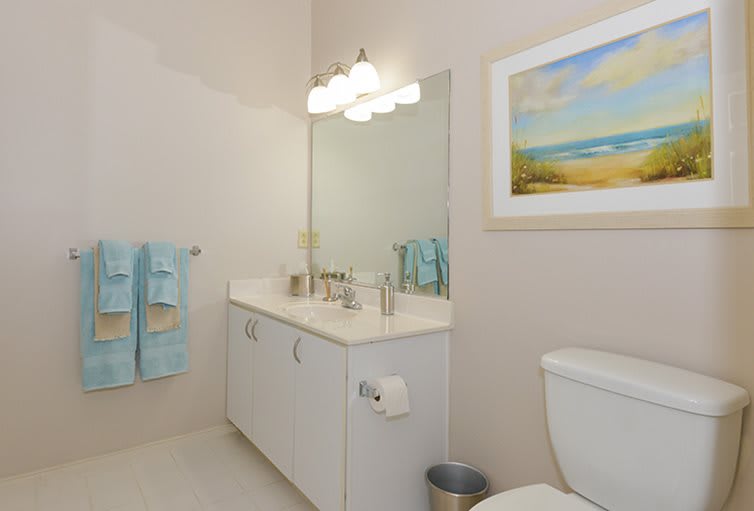 A modern bathroom with a sink, mirror, and neatly arranged towels.