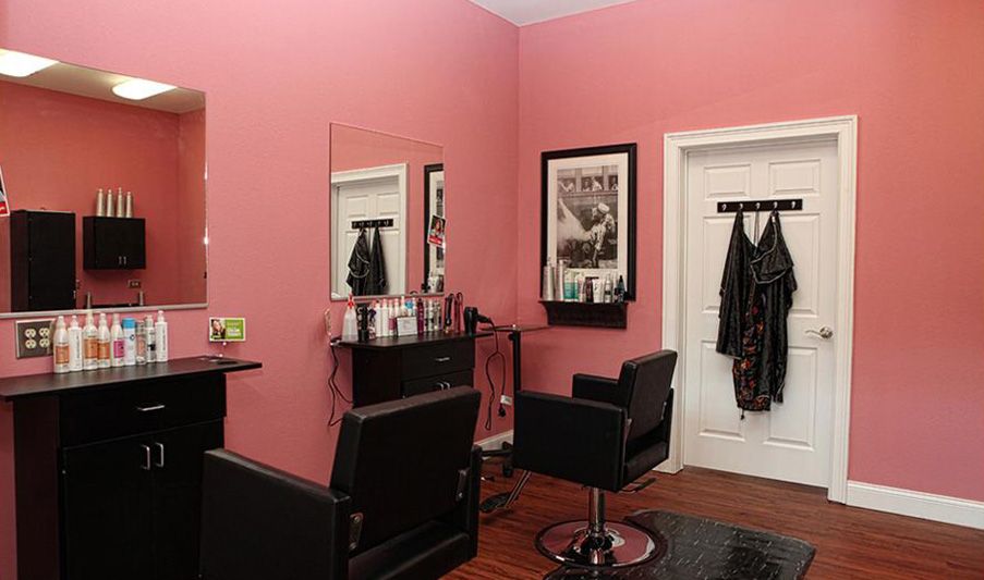 A cozy salon with pink walls, mirrors, and stylish black chairs.