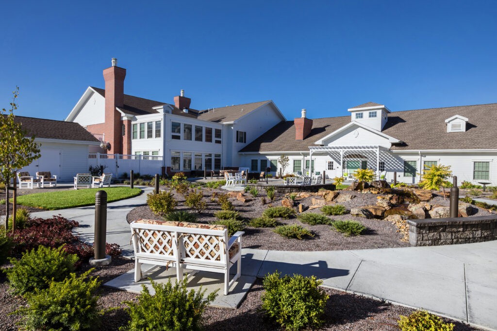 A sunny day at a well-maintained building with a landscaped garden and benches.