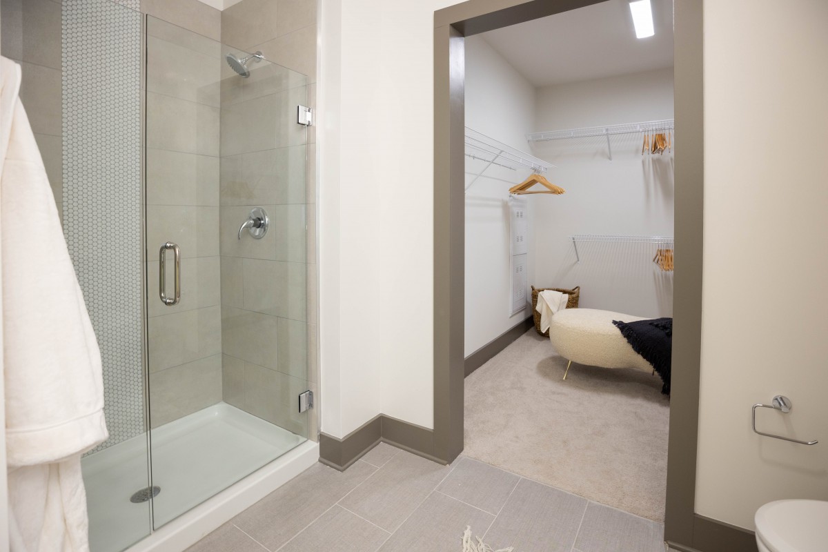 A modern bathroom with a glass shower and adjoining dressing area.