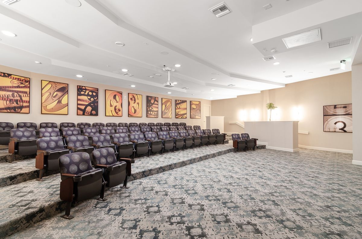 A spacious theater room with multiple rows of seating and a projector.