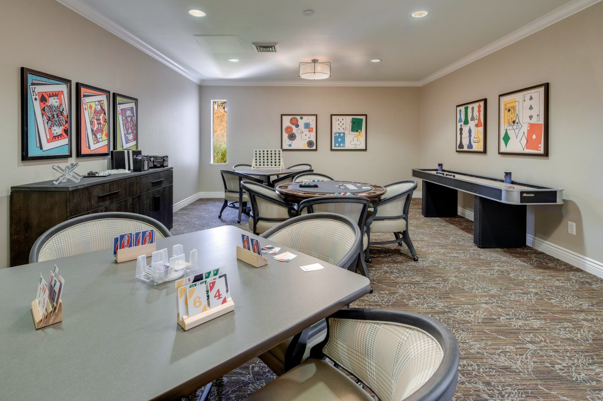 A cozy game room featuring multiple tables, chairs, and wall artwork.