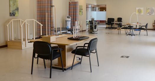 A rehabilitation therapy room with exercise equipment and seating.