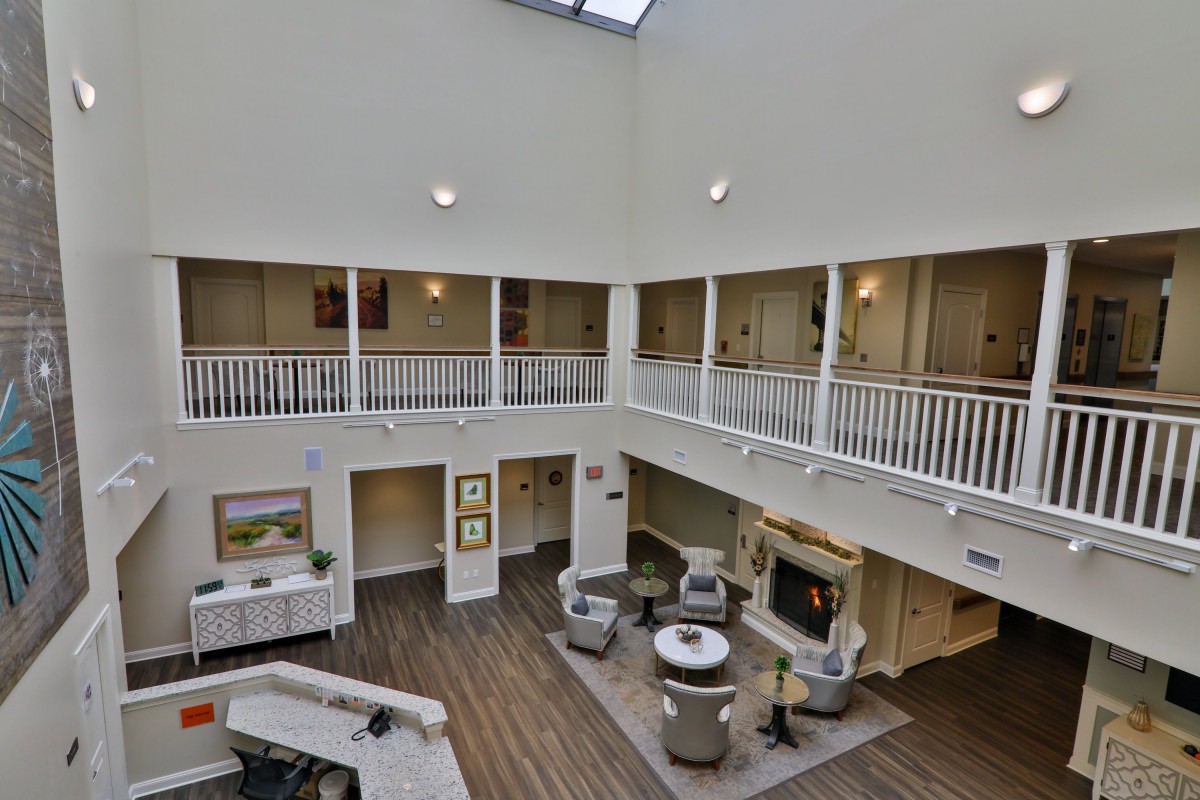 A spacious, two-story atrium with a skylight, featuring a comfortable seating area and balconies.