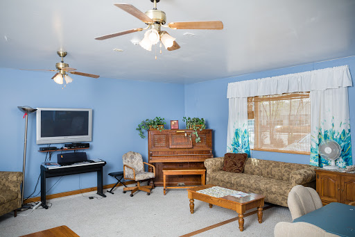 A cozy living room featuring a piano, comfortable sofa, and blue walls.
