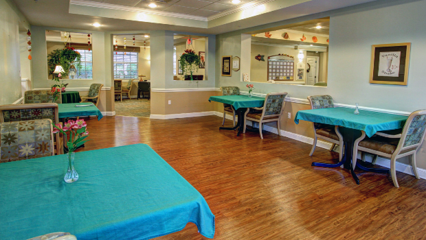 An indoor dining area with neatly arranged tables and chairs on a wooden floor.