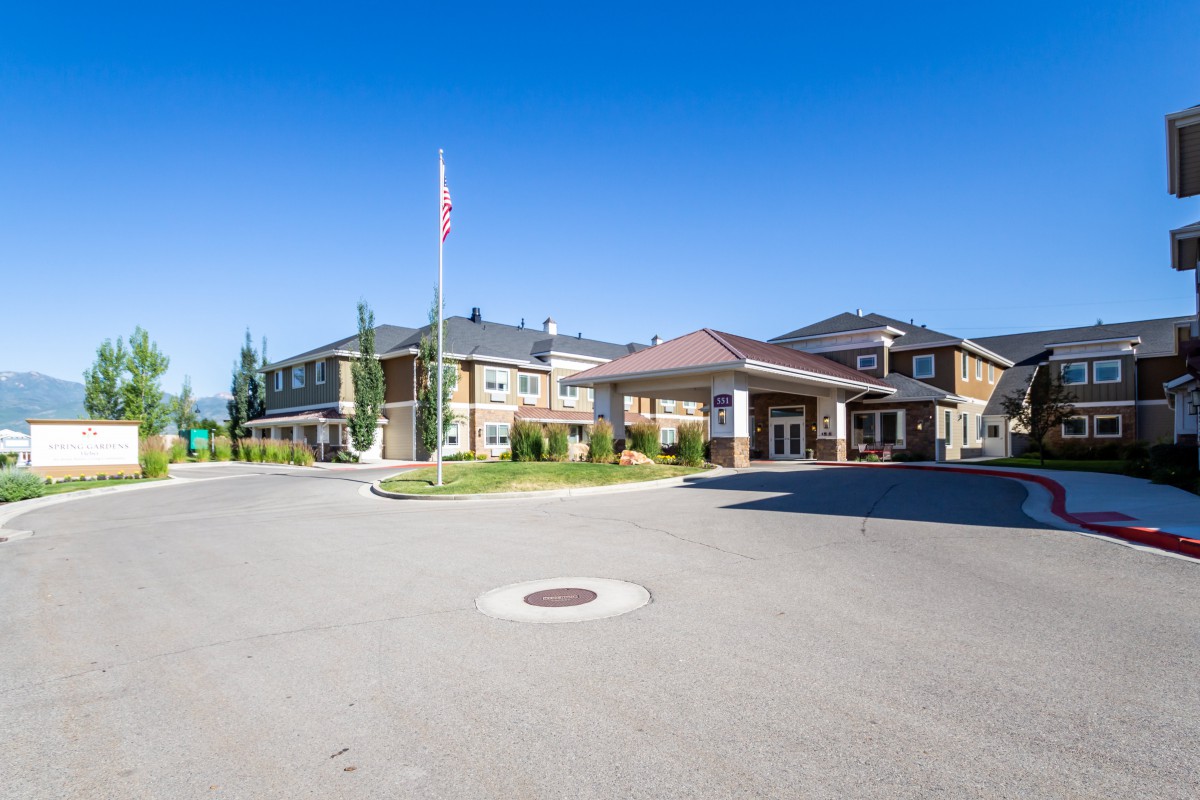 A large building with an entrance and driveway, featuring a flagpole against a clear blue sky.