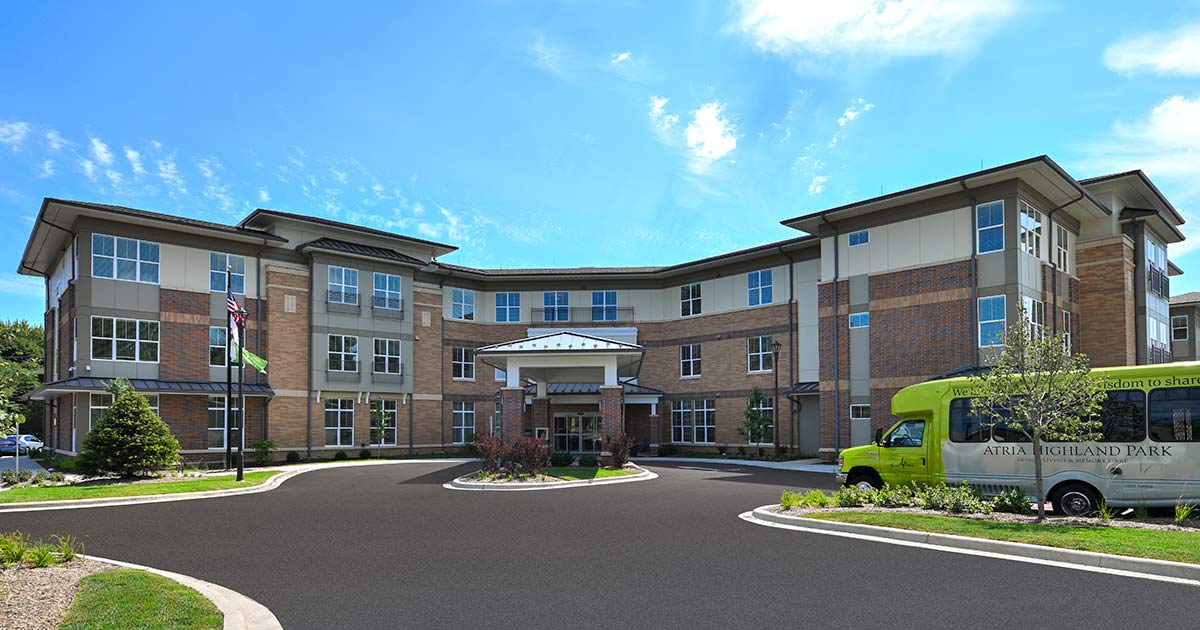 A modern multi-story building with a curved facade and a clear blue sky overhead.