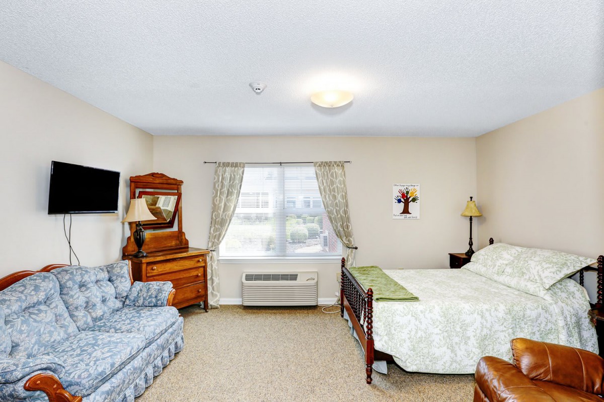 A cozy bedroom with a bed, sofa, and wooden furniture.