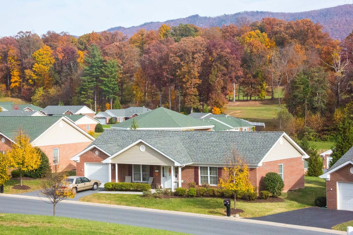 A suburban neighborhood with houses surrounded by colorful autumn trees and mountains in the background.