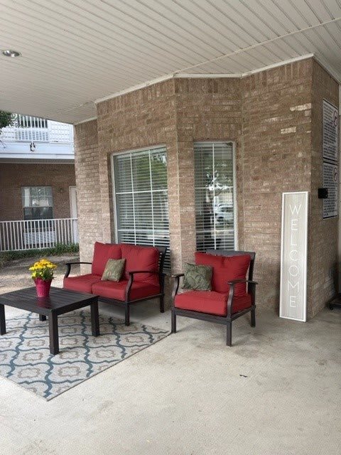An inviting outdoor patio setup with red-cushioned furniture and a decorative rug.