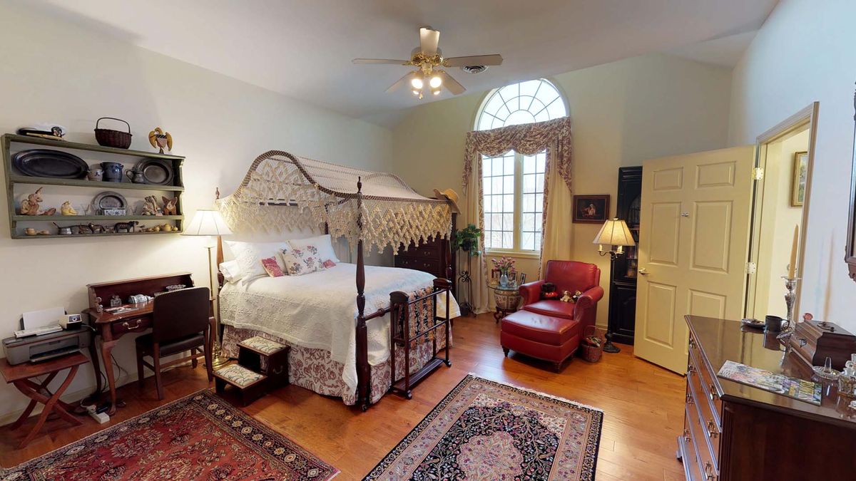 A cozy vintage-style bedroom featuring a four-poster bed and a comfortable armchair.