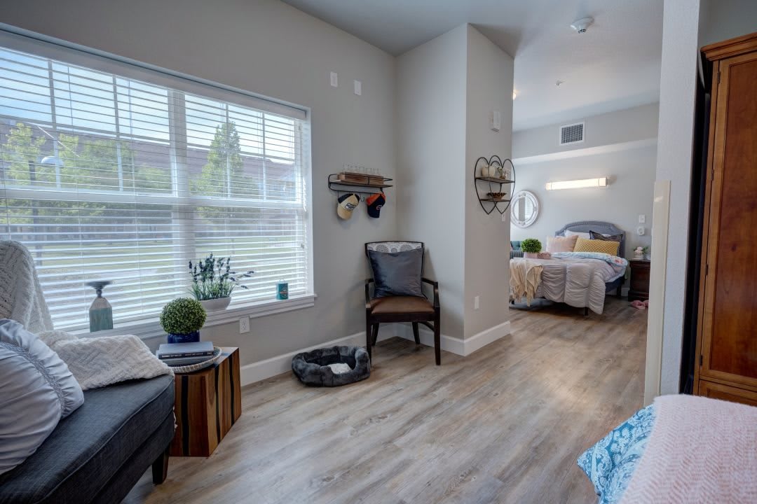 A modern apartment interior featuring a cozy bedroom and living area with hardwood floors and ample natural light.